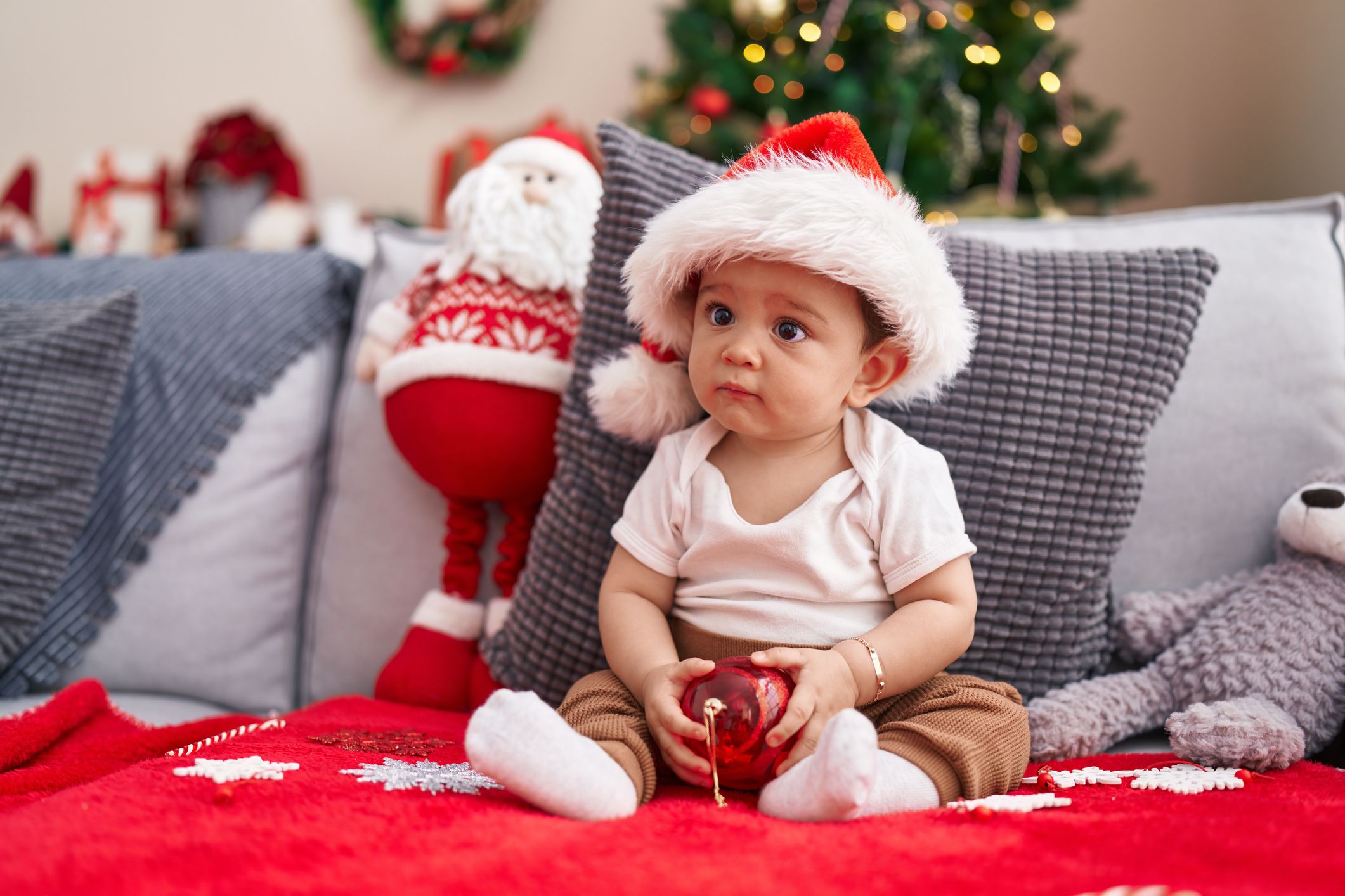 Baby sat on sofa with santa hat.