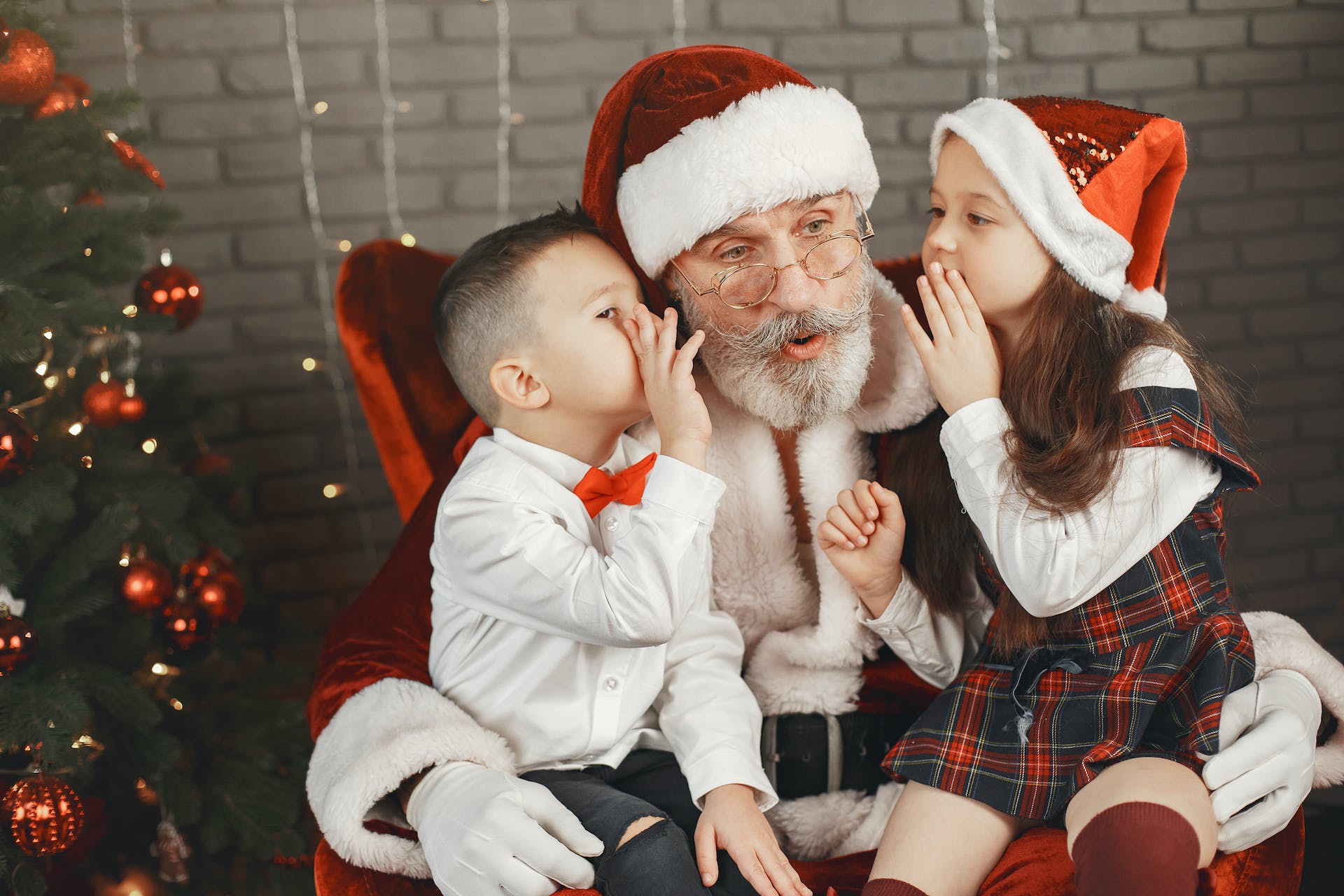 Toddler whispering in santa's ear.