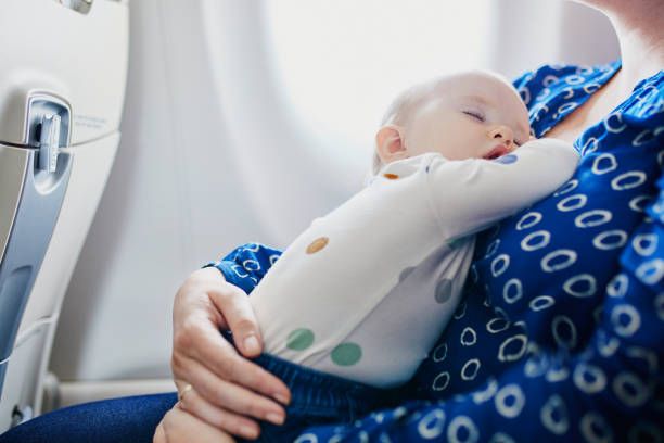 baby on mums lap in a plane.