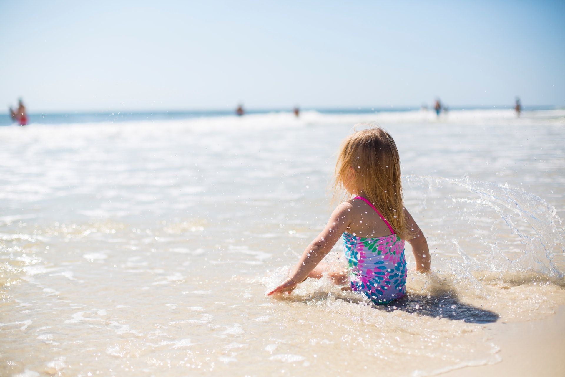A little girl splashes in the sea.