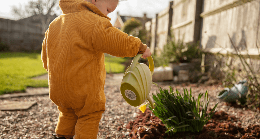 Small child watering the garden and learning to count with nature