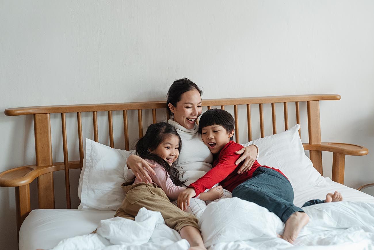 mum cuddling her children in bed, one child on each side of her