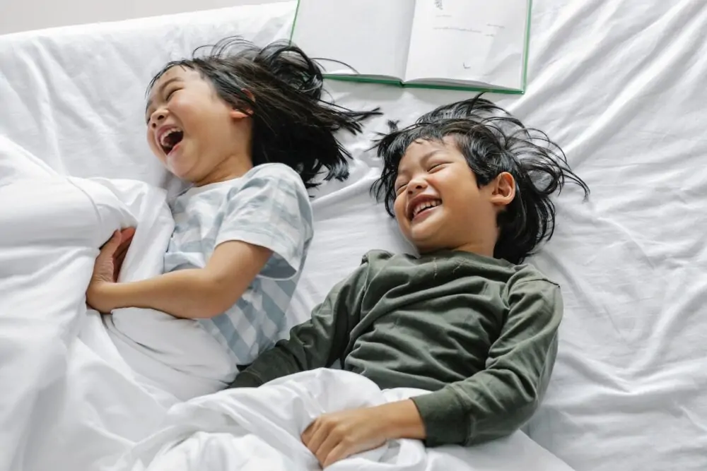 Two kids laughing in bed.